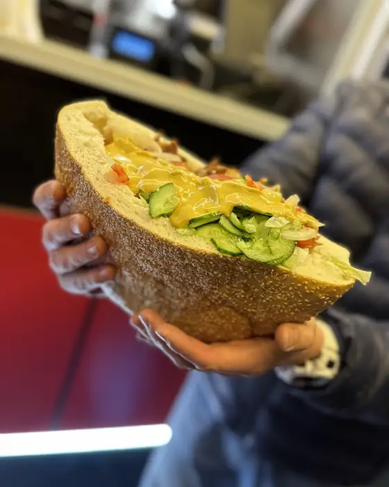 Kebab w bułce trzymany w dłoni, ze świeżymi warzywami